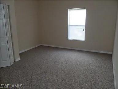 Empty room featuring carpet flooring and baseboards