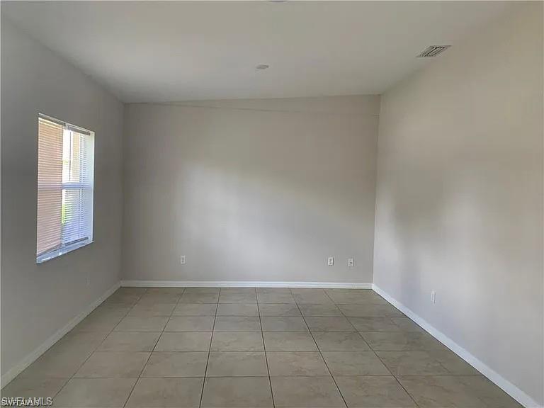 Spare room with light tile patterned flooring, visible vents, and baseboards