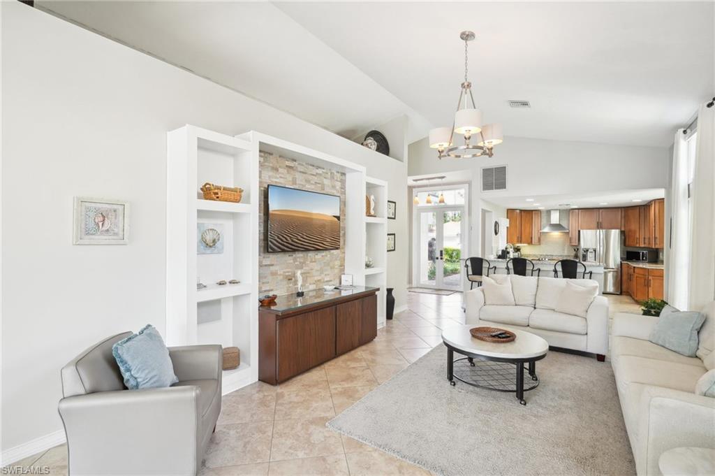 Living area featuring built in shelves, visible vents, a notable chandelier, and light tile patterned floors