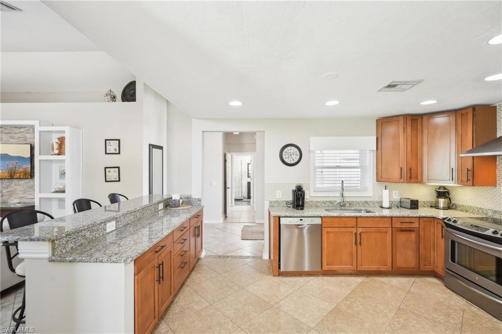 Kitchen with a breakfast bar area, stainless steel appliances, a sink, visible vents, and decorative backsplash