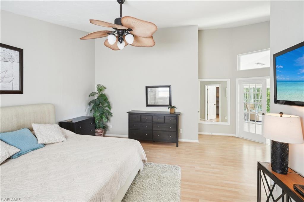 Bedroom featuring a ceiling fan, a high ceiling, baseboards, and wood finished floors