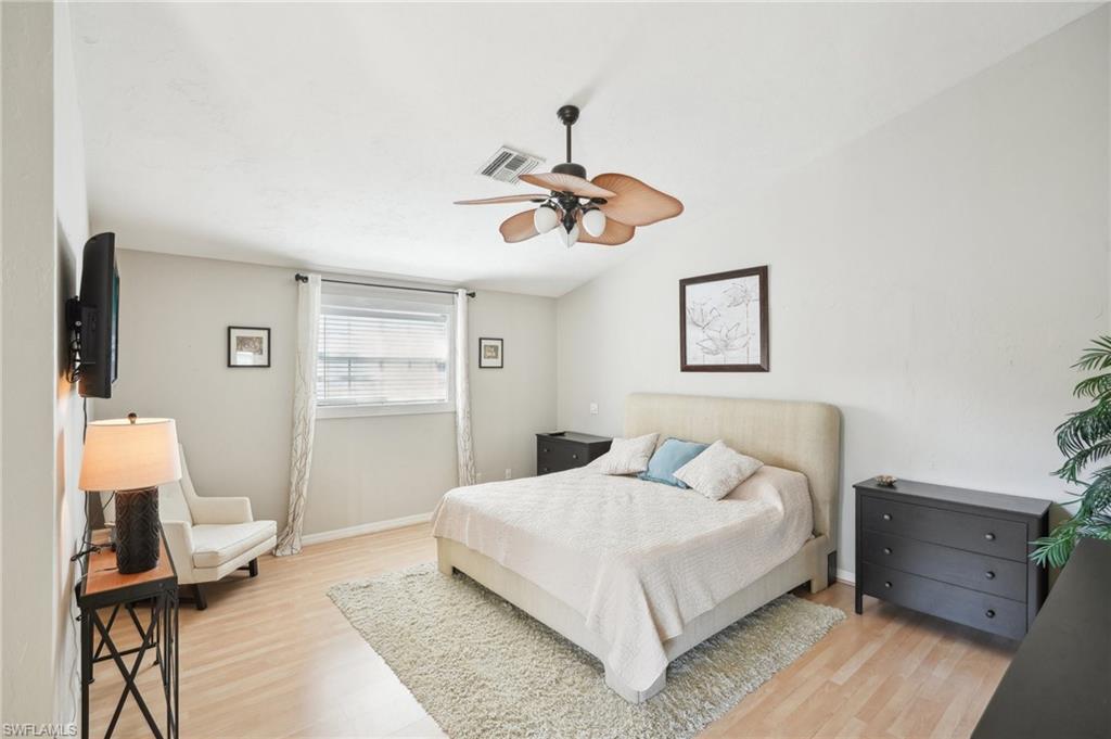 Bedroom featuring visible vents, light wood-style floors, vaulted ceiling, ceiling fan, and baseboards