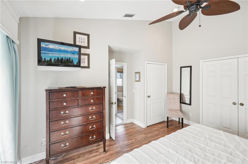 Bedroom with a closet, visible vents, vaulted ceiling, wood finished floors, and baseboards