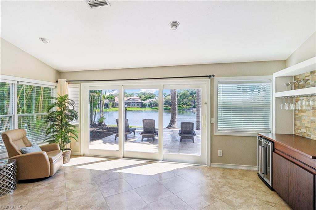 Doorway with lofted ceiling, visible vents, a water view, light tile patterned flooring, and baseboards