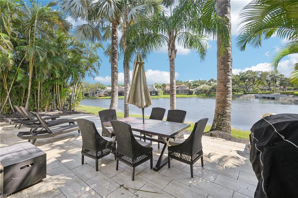View of patio with outdoor dining area, a water view, and a grill