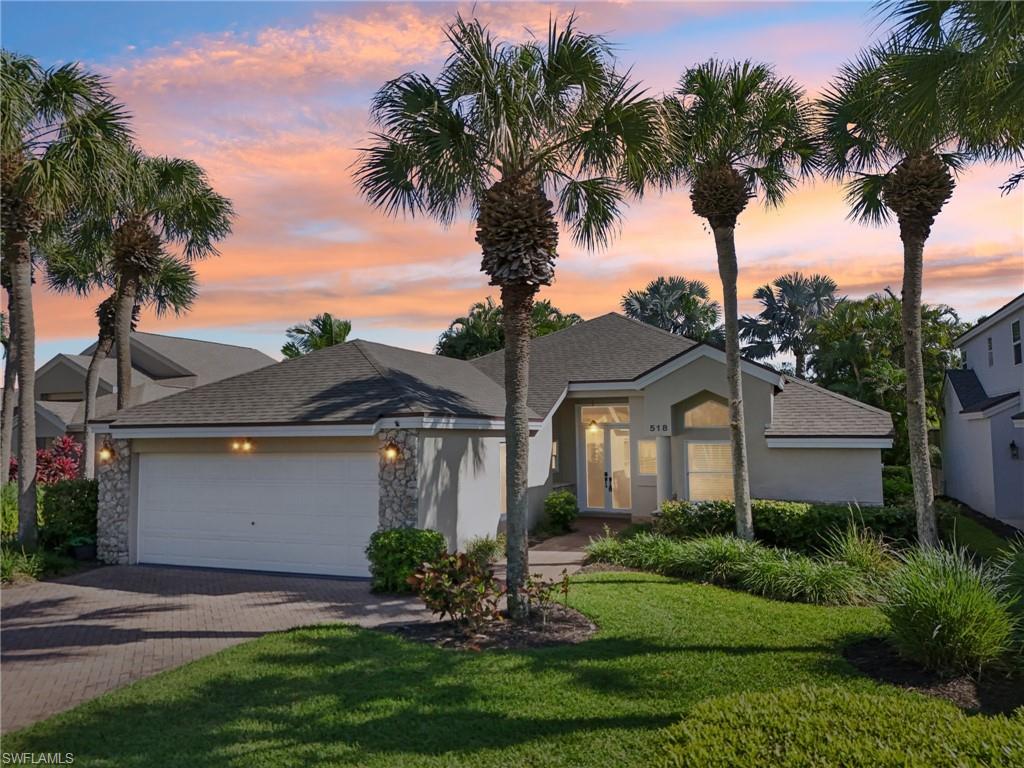 View of front facade featuring decorative driveway, roof with shingles, stucco siding, an attached garage, and a front yard