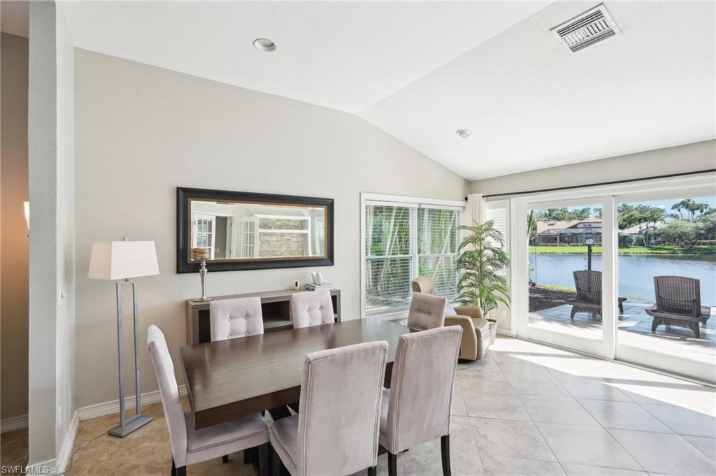 Dining room featuring baseboards, visible vents, lofted ceiling, a water view, and light tile patterned flooring