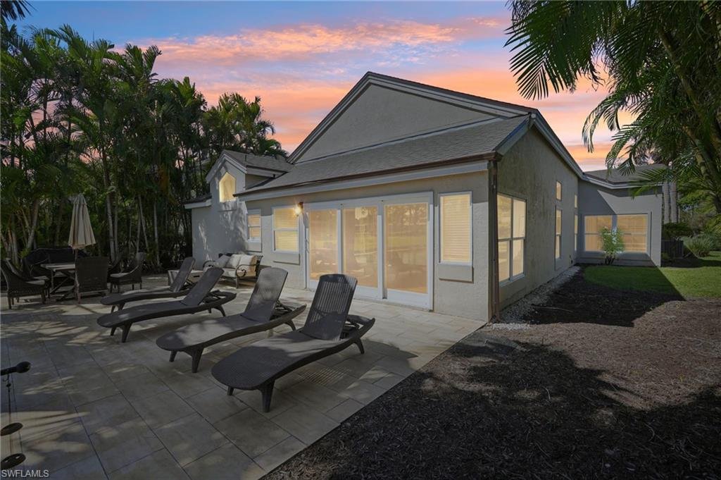Back of property at dusk with a patio and stucco siding