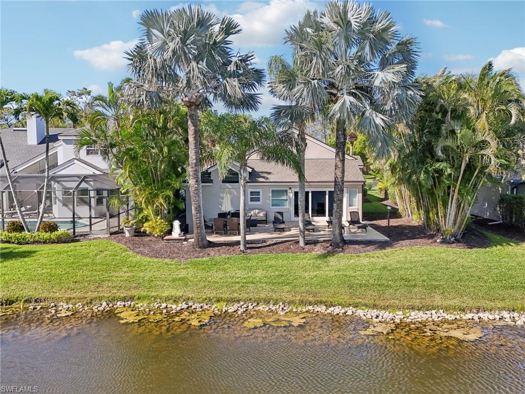 Back of property featuring a lawn, a patio area, a lanai, and a water view