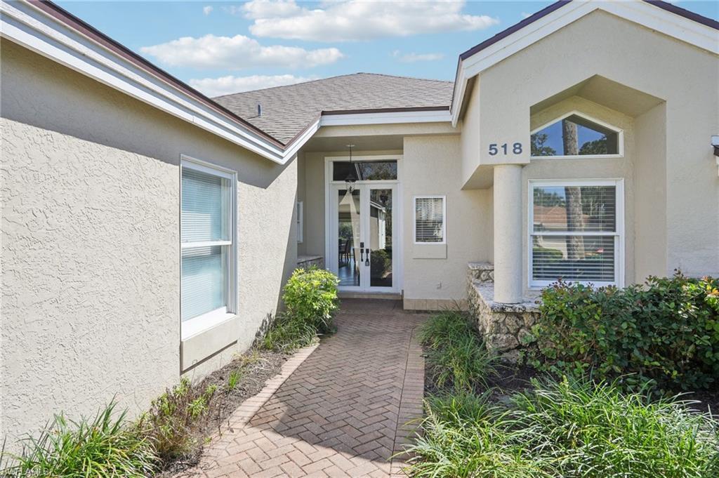 Property entrance featuring stucco siding, roof with shingles, and french doors