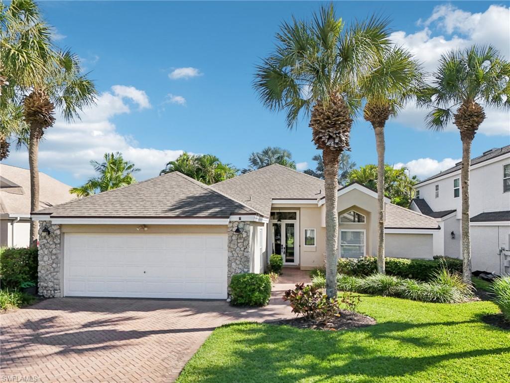 View of front of property with decorative driveway, stucco siding, an attached garage, stone siding, and a front lawn