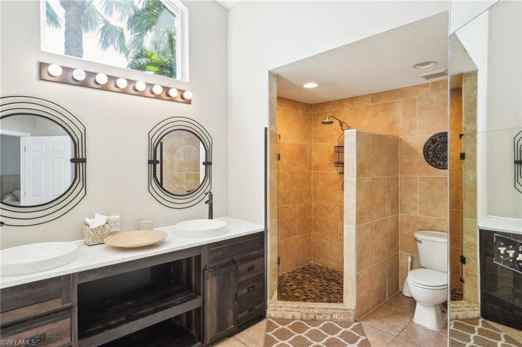 Full bath featuring double vanity, tiled shower, a sink, and tile patterned floors