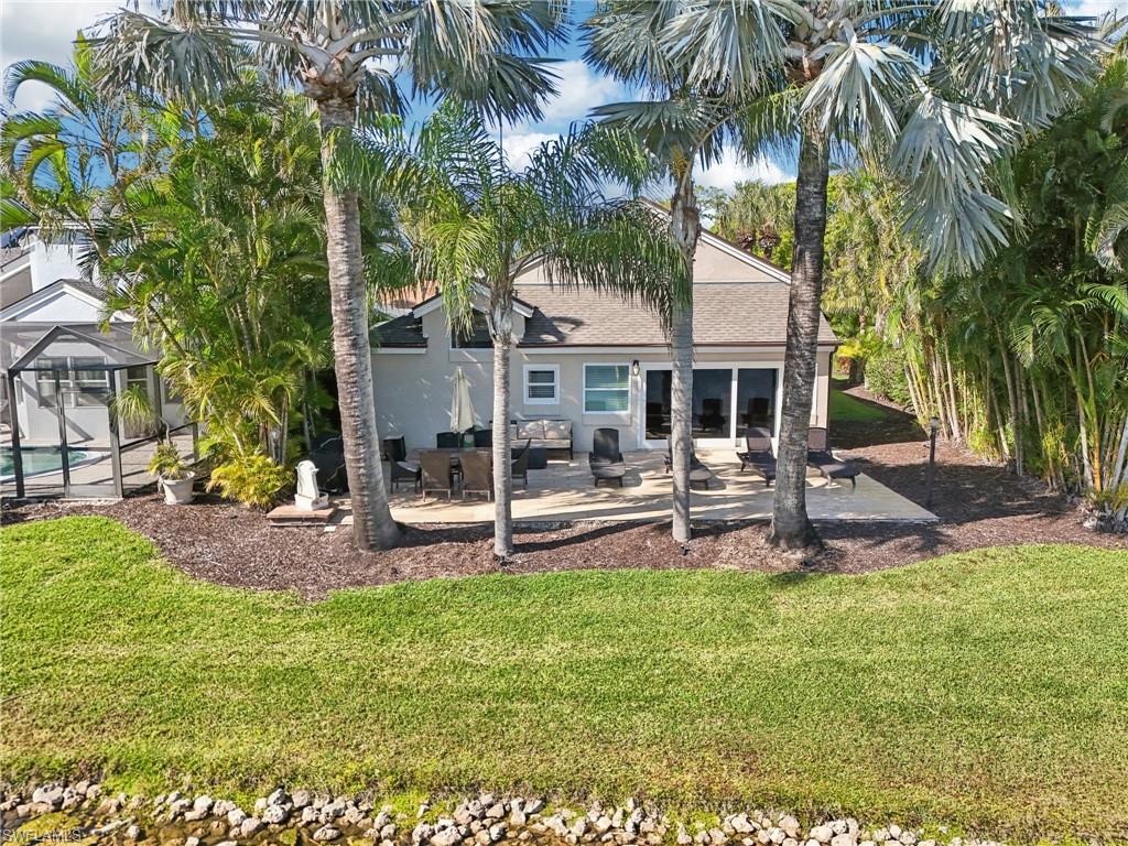 Rear view of house featuring a lanai, a patio area, a yard, and stucco siding