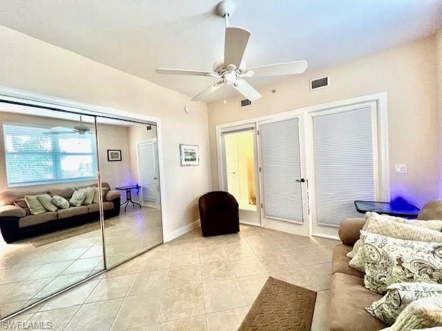Living room with light tile patterned floors, visible vents, baseboards, and ceiling fan