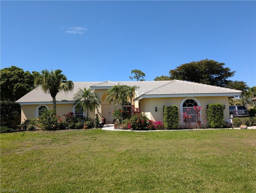 View of front of house featuring stucco siding, a tile roof, and a large front lawn