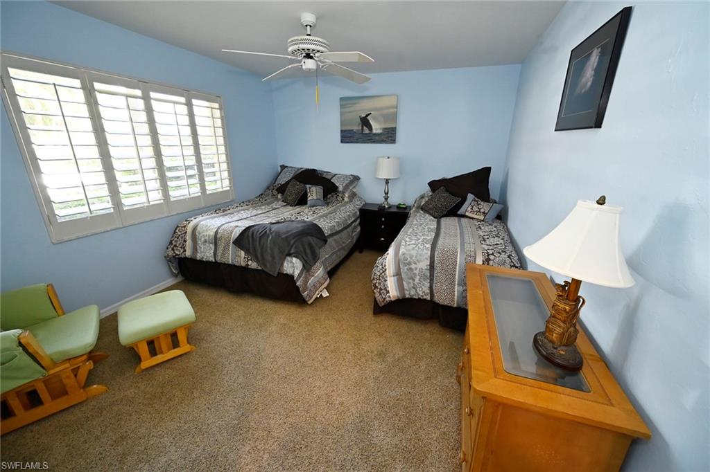 Carpeted bedroom with ceiling fan, plantation shutters.