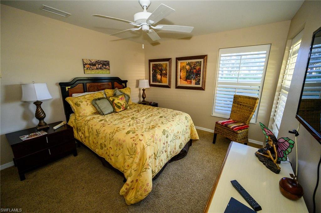 Bedroom featuring carpet, and ceiling fan and plantation shutters.