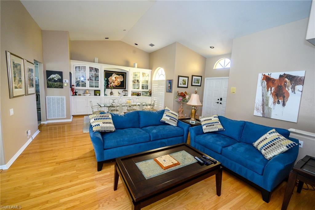 The living/dining combo space features lofted ceiling, and light wood-style floors, sliders out to the lanai.