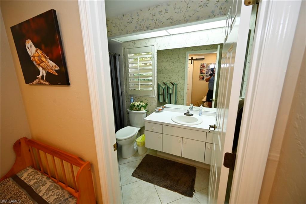 Guest bathroom with walk-in shower, tile floors, and plantation shutter.