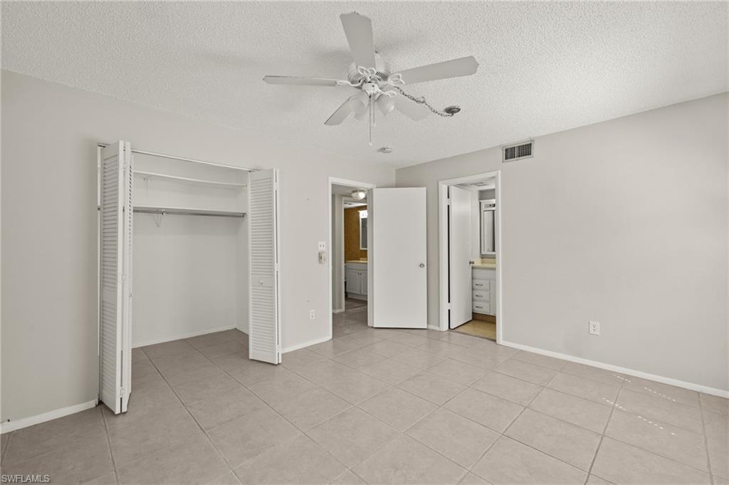 Unfurnished bedroom featuring a closet, a textured ceiling, visible vents, and a ceiling fan