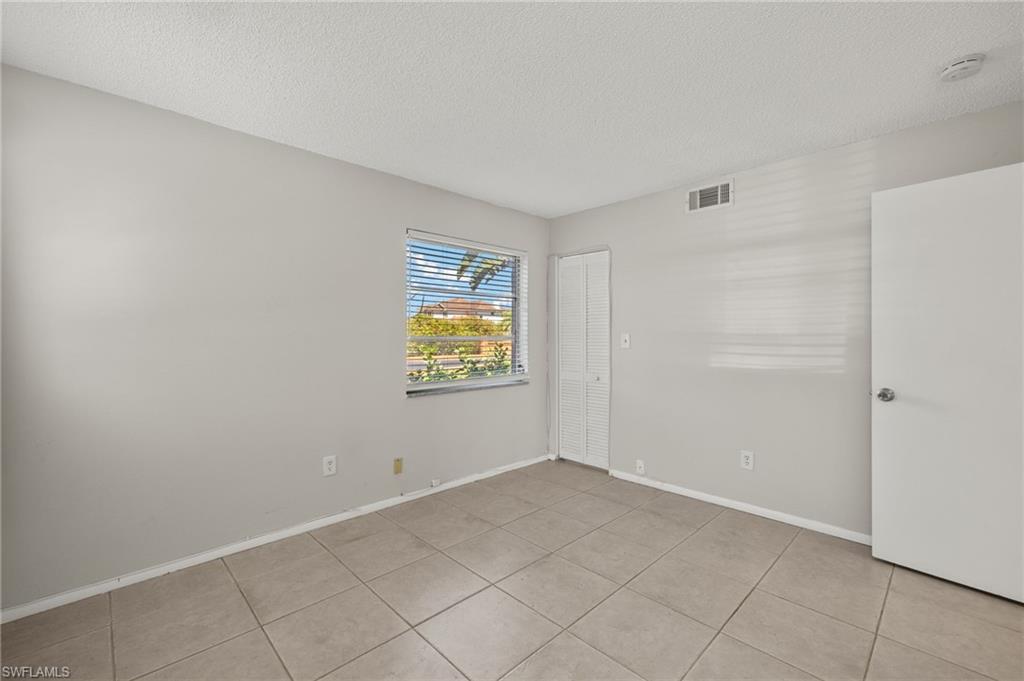 Unfurnished room with light tile patterned flooring, baseboards, visible vents, and a textured ceiling
