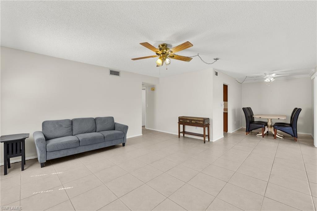 Living area featuring light tile patterned floors, visible vents, a textured ceiling, and ceiling fan