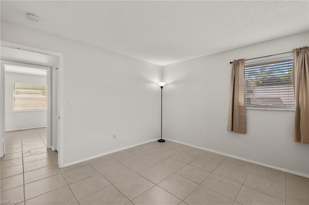 Unfurnished room featuring light tile patterned floors, baseboards, and a textured ceiling