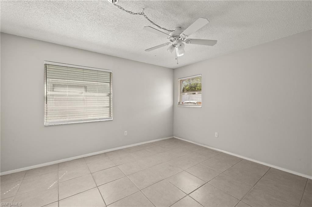 Tiled spare room with a textured ceiling, baseboards, and ceiling fan