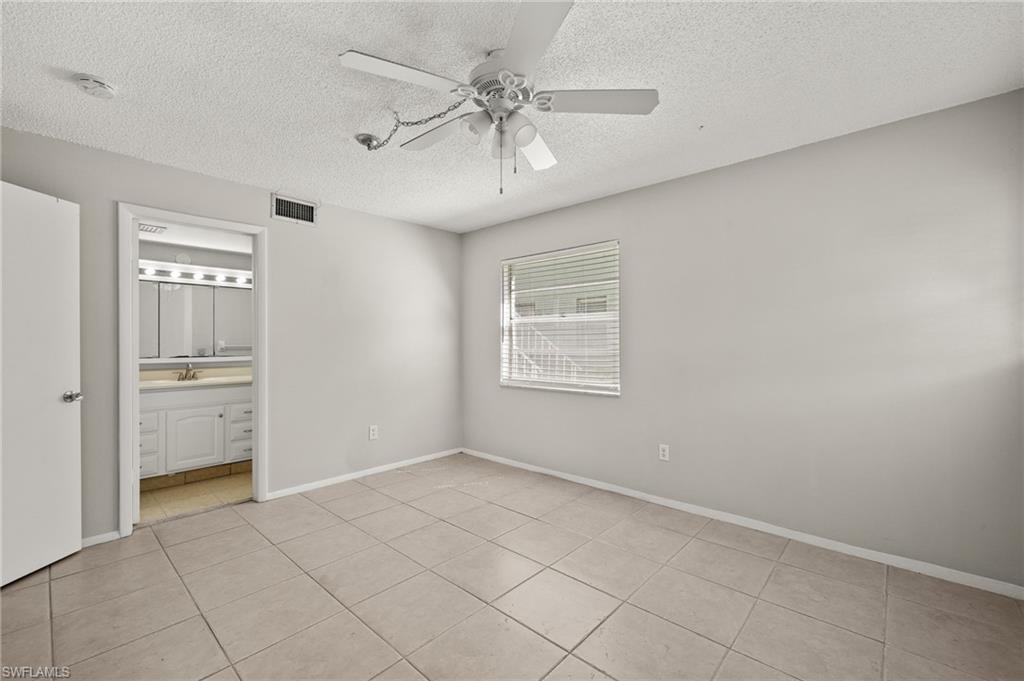 Unfurnished bedroom with light tile patterned floors, baseboards, visible vents, ceiling fan, and a textured ceiling