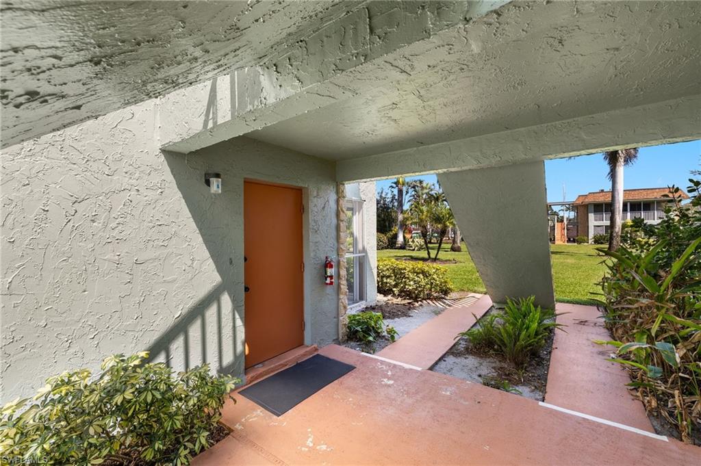 Doorway to property featuring stucco siding and a yard