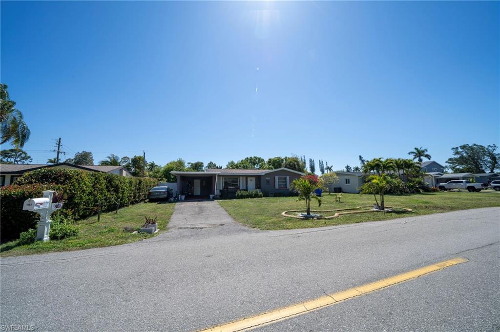View of front of house featuring aphalt driveway, a carport, and a front lawn