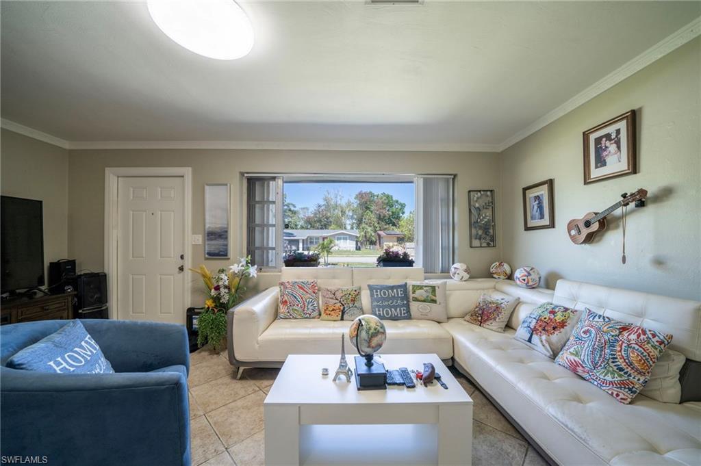 Living room with light tile patterned floors and crown molding