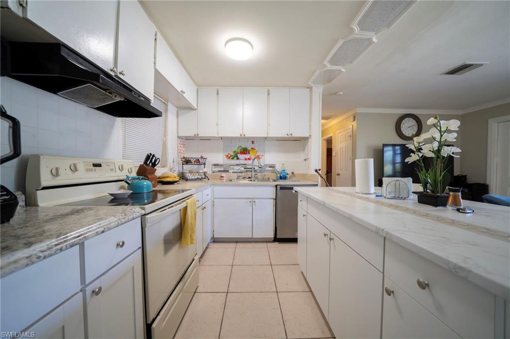 Kitchen featuring white range with electric stovetop, visible vents, white cabinetry, and a sink