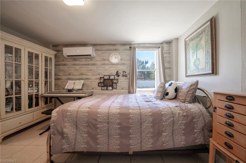Bedroom featuring an AC wall unit, light tile patterned floors, and wood walls