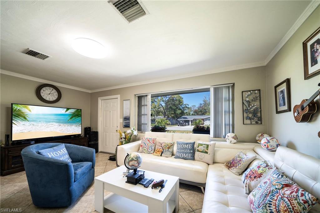 Living area featuring tile patterned floors, visible vents, and crown molding