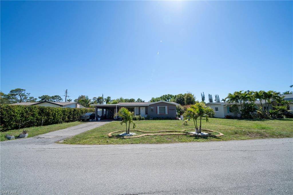 View of front of property featuring a carport, driveway, and a front lawn