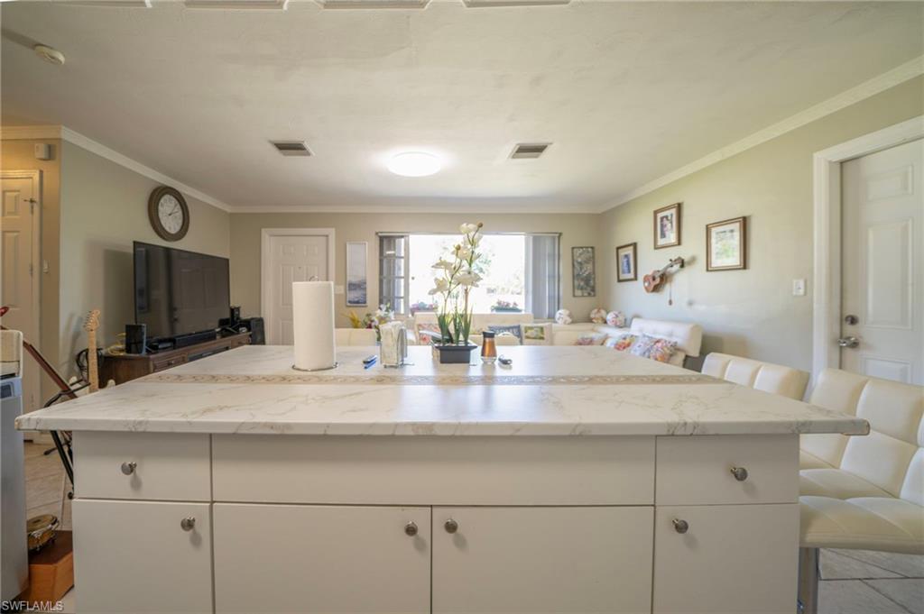 Kitchen with visible vents, white cabinets, open floor plan, and ornamental molding