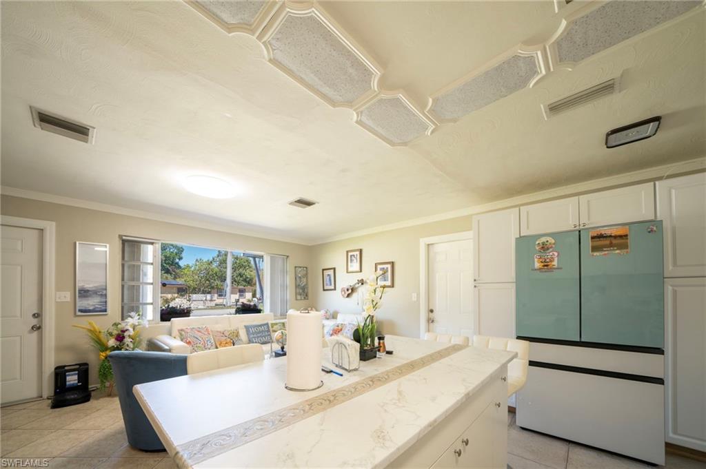 Kitchen with light tile patterned flooring, visible vents, and fridge
