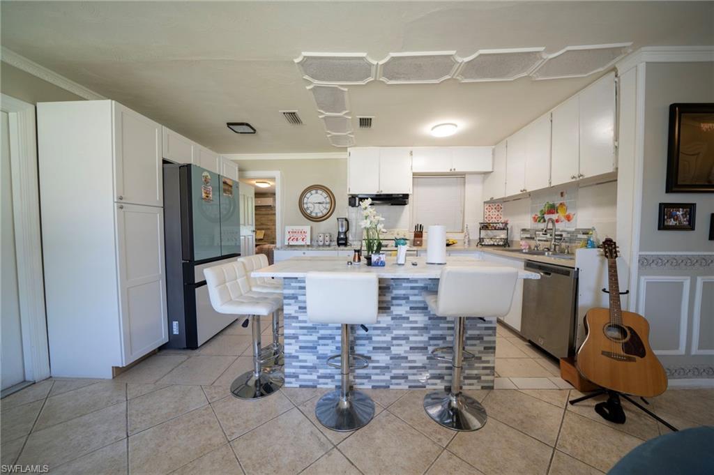 Kitchen featuring visible vents, light tile patterned flooring, light countertops, appliances with stainless steel finishes, and white cabinetry