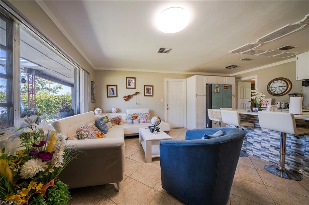 Living room featuring visible vents, ornamental molding, and light tile patterned flooring