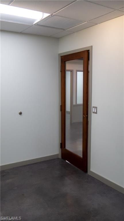Spare room with baseboards, a paneled ceiling, and concrete flooring