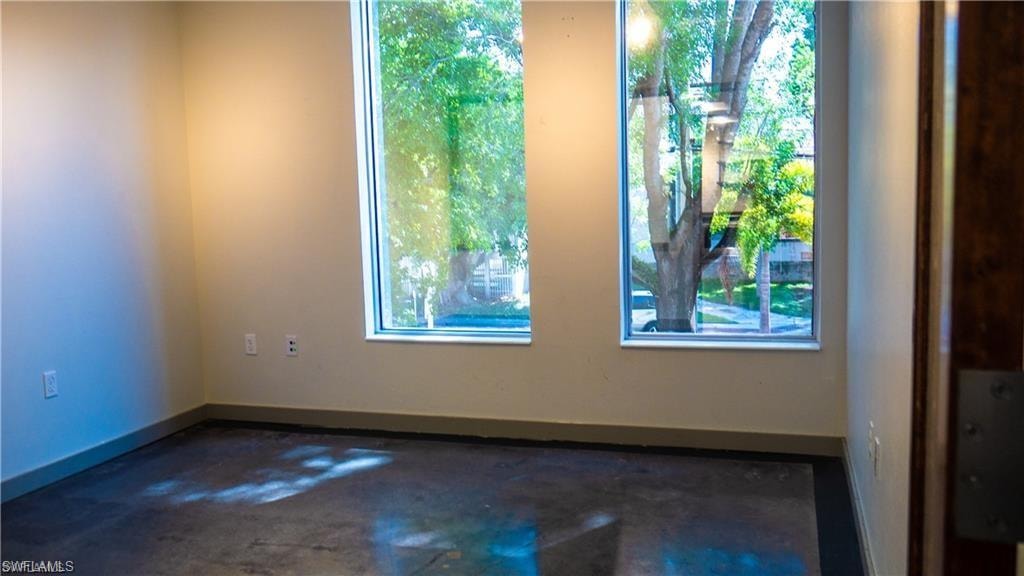 Unfurnished room with baseboards and concrete flooring