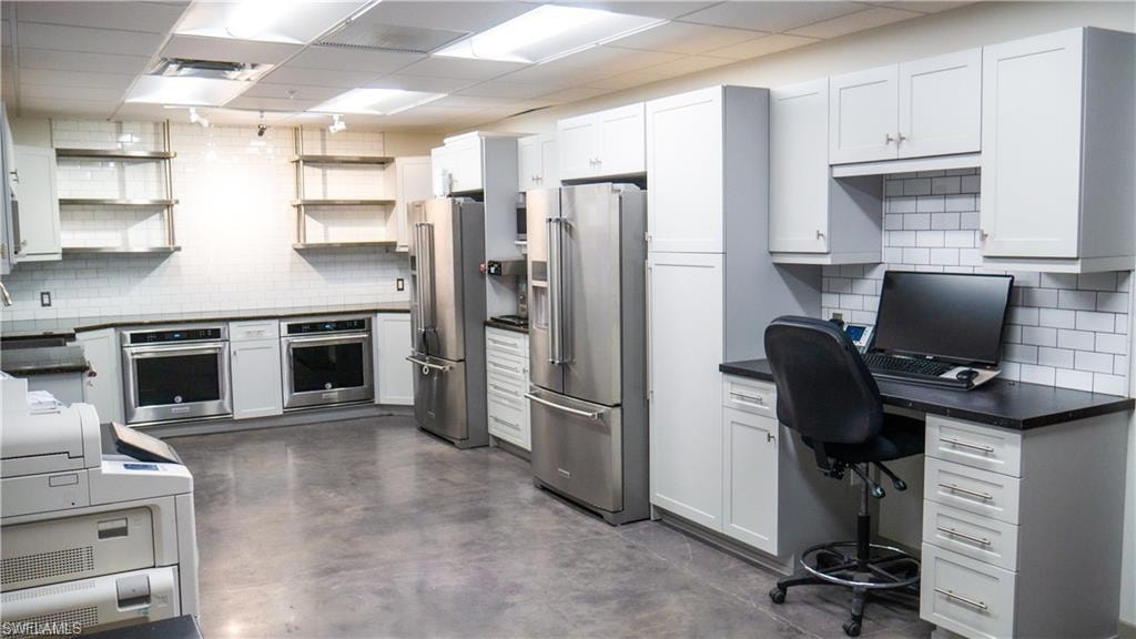 Kitchen with open shelves, stainless steel appliances, dark countertops, and decorative backsplash