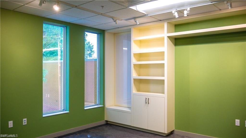 Spare room featuring built in features, track lighting, and baseboards