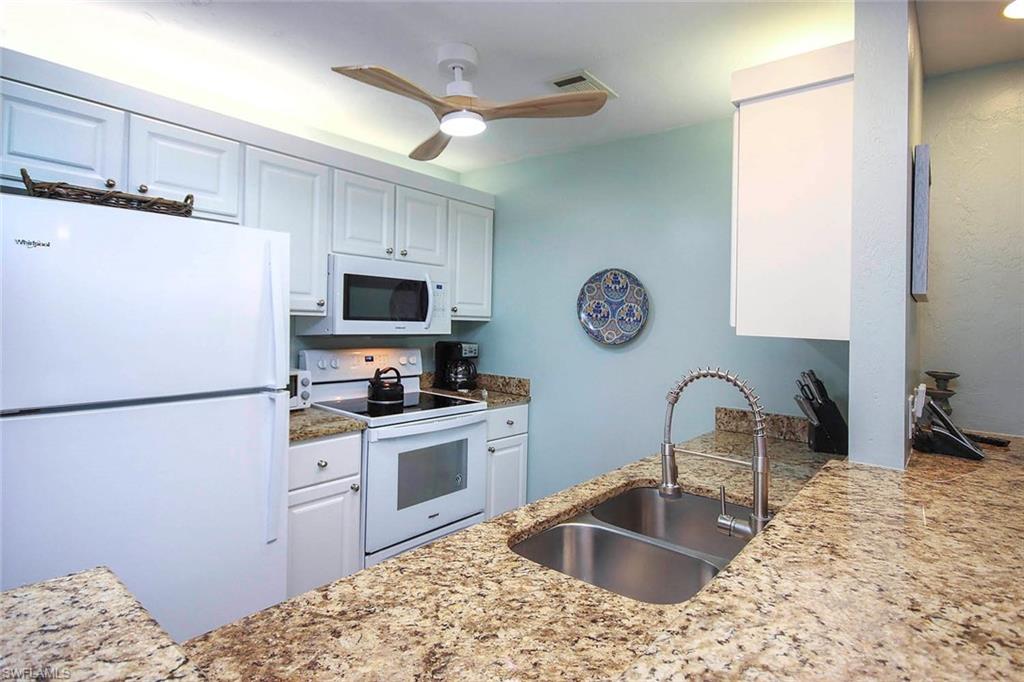 Kitchen featuring white appliances, visible vents, ceiling fan, a sink, and white cabinets