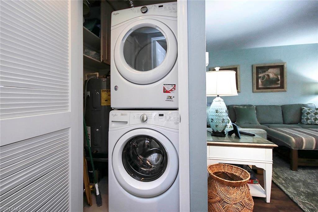 Clothes washing area featuring stacked washer / drying machine and wood finished floors