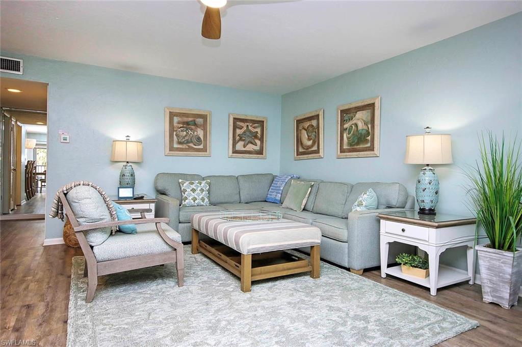 Living room with wood finished floors, a ceiling fan, visible vents, and baseboards