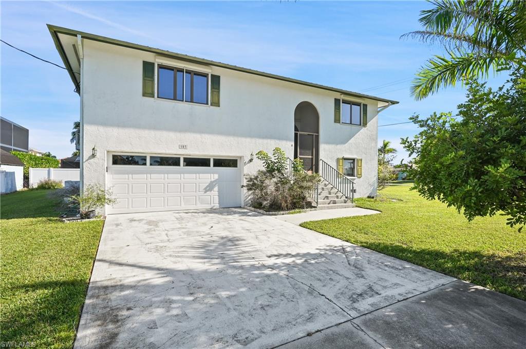 View of front of property featuring driveway, a front lawn, and an attached garage