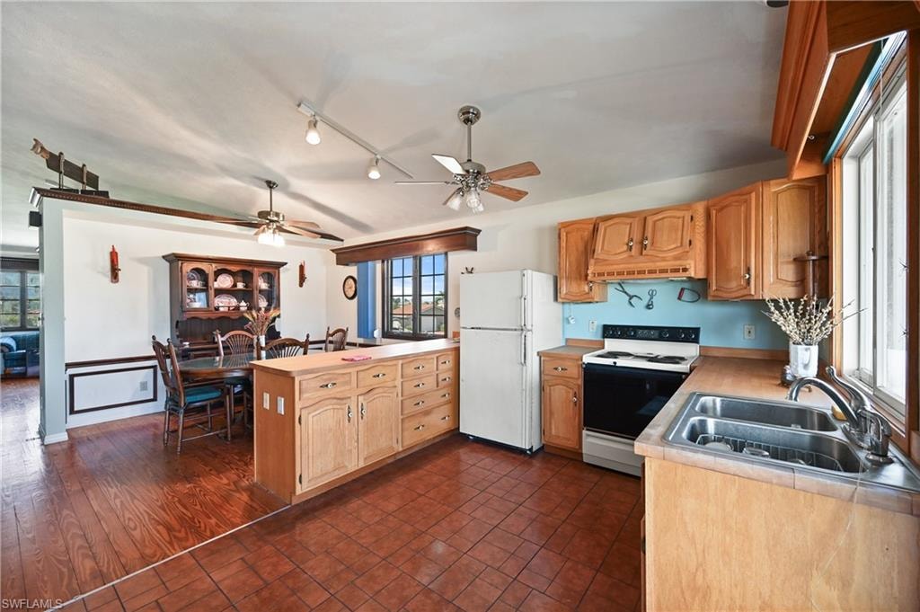 Kitchen with white appliances, light countertops, ceiling fan, and track lighting