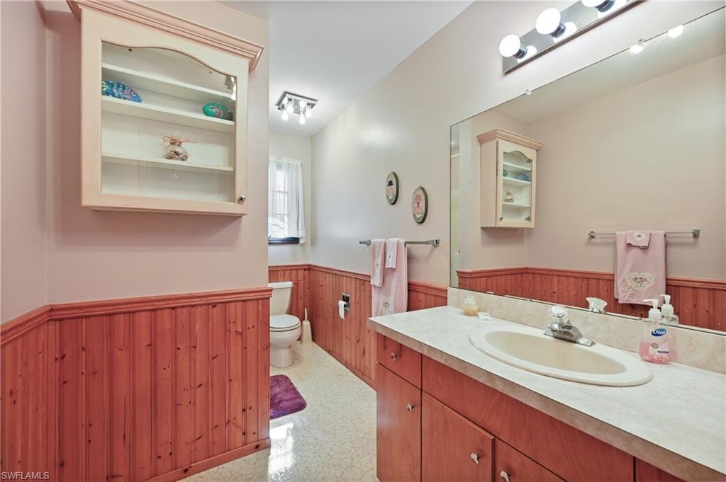 Bathroom featuring wood walls, a wainscoted wall, and vanity
